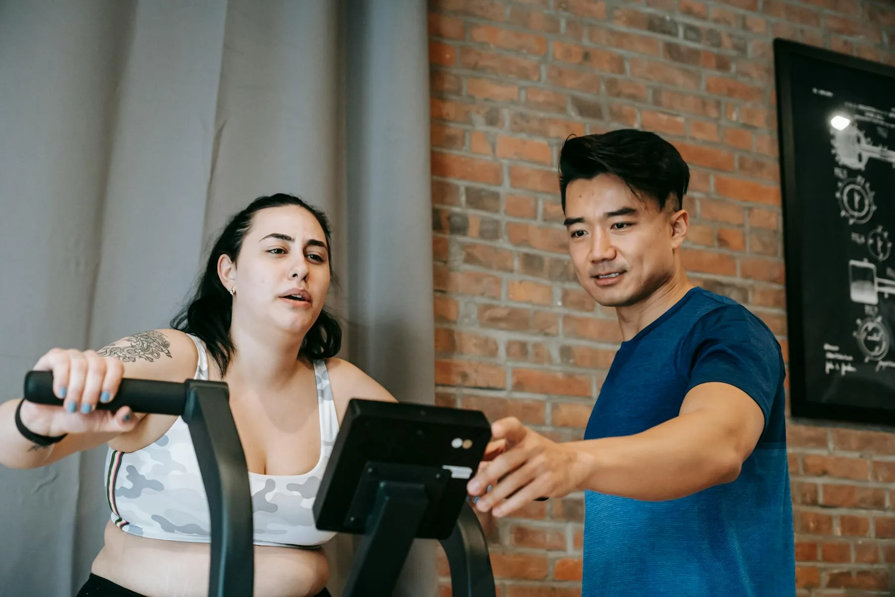 Trainer guiding a client through steady cardio work in a gym.