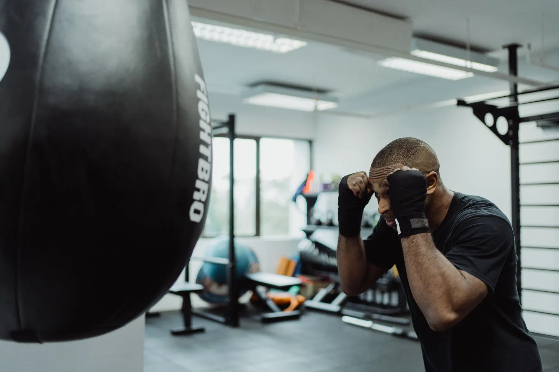 Boxer holding a compact guard while working in front of a punching bag.