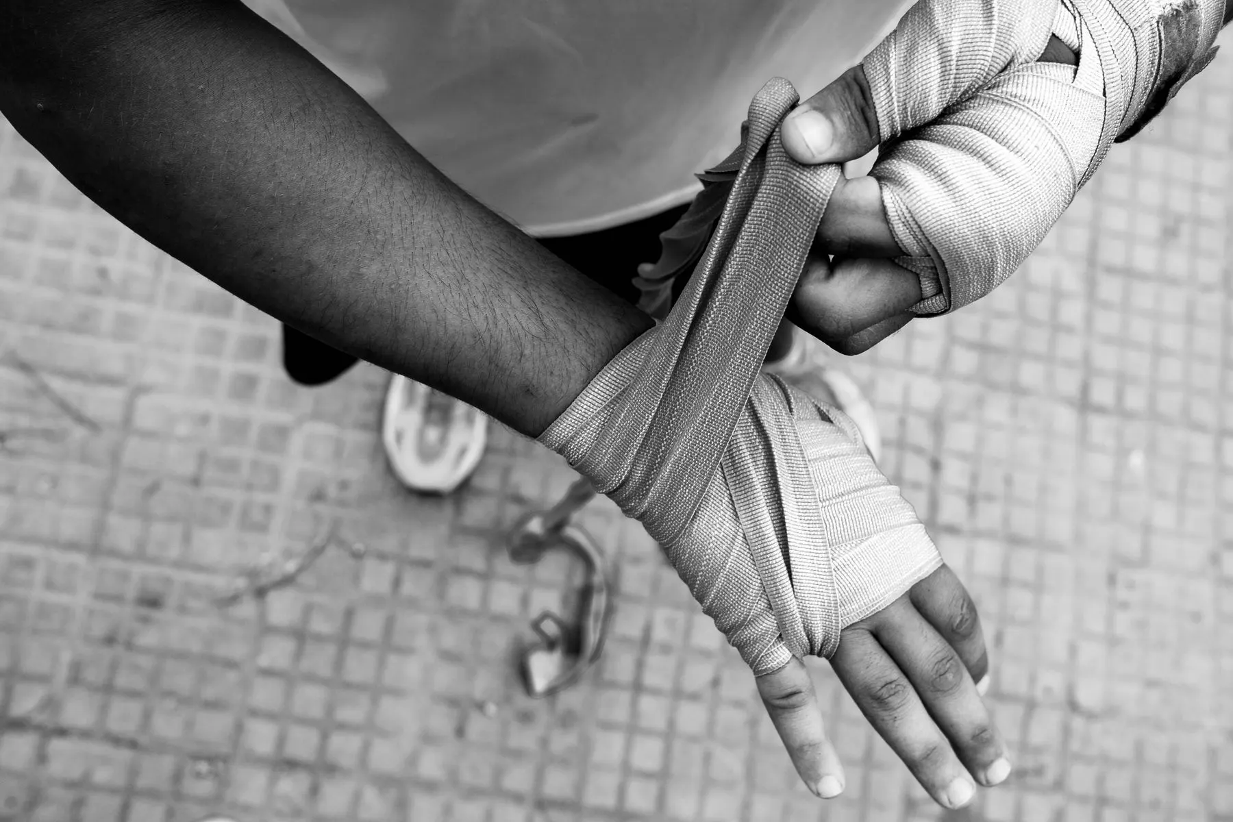 Close-up of a boxer securing cloth hand wraps before training.