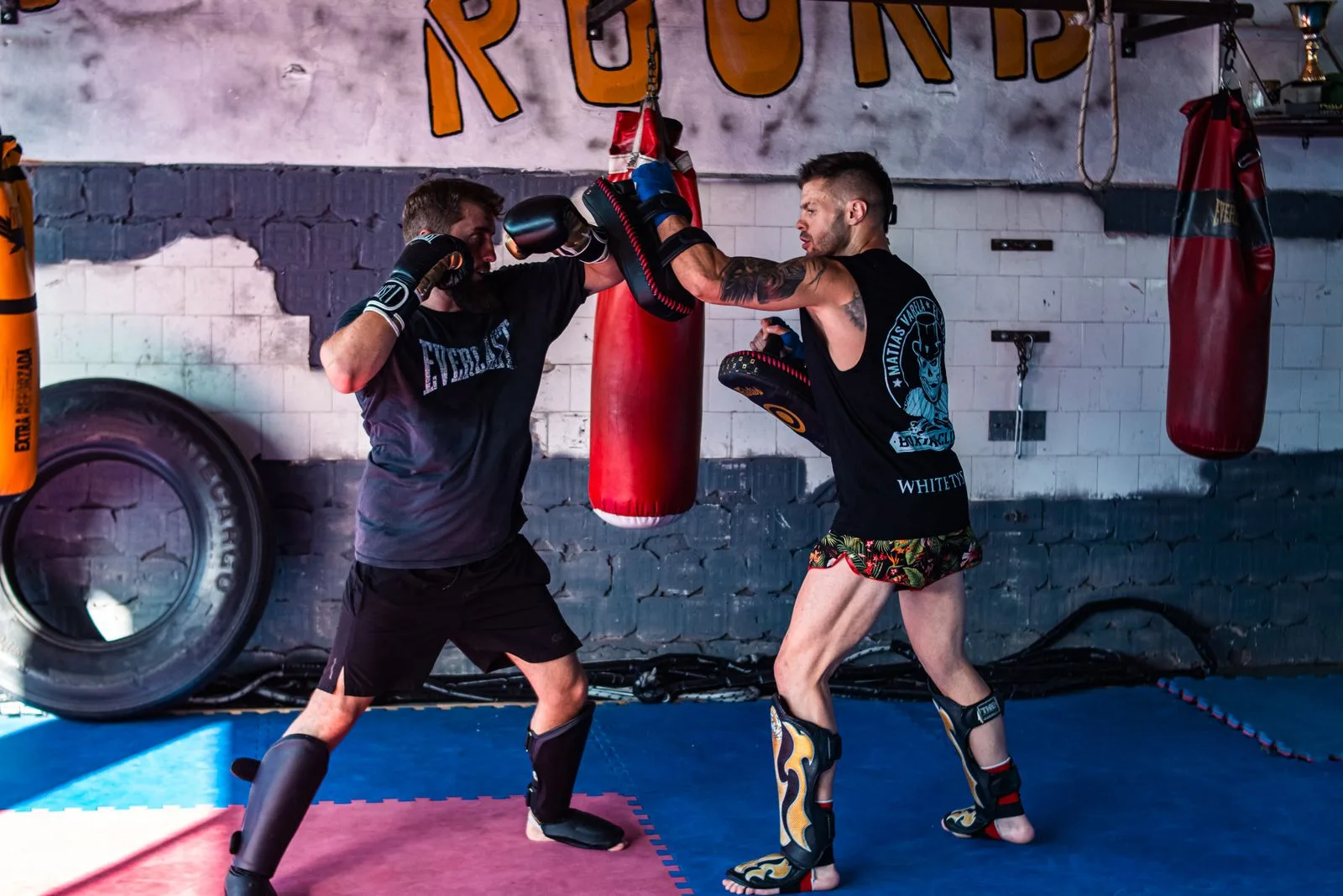 Two people training with boxing gloves in a gym.
