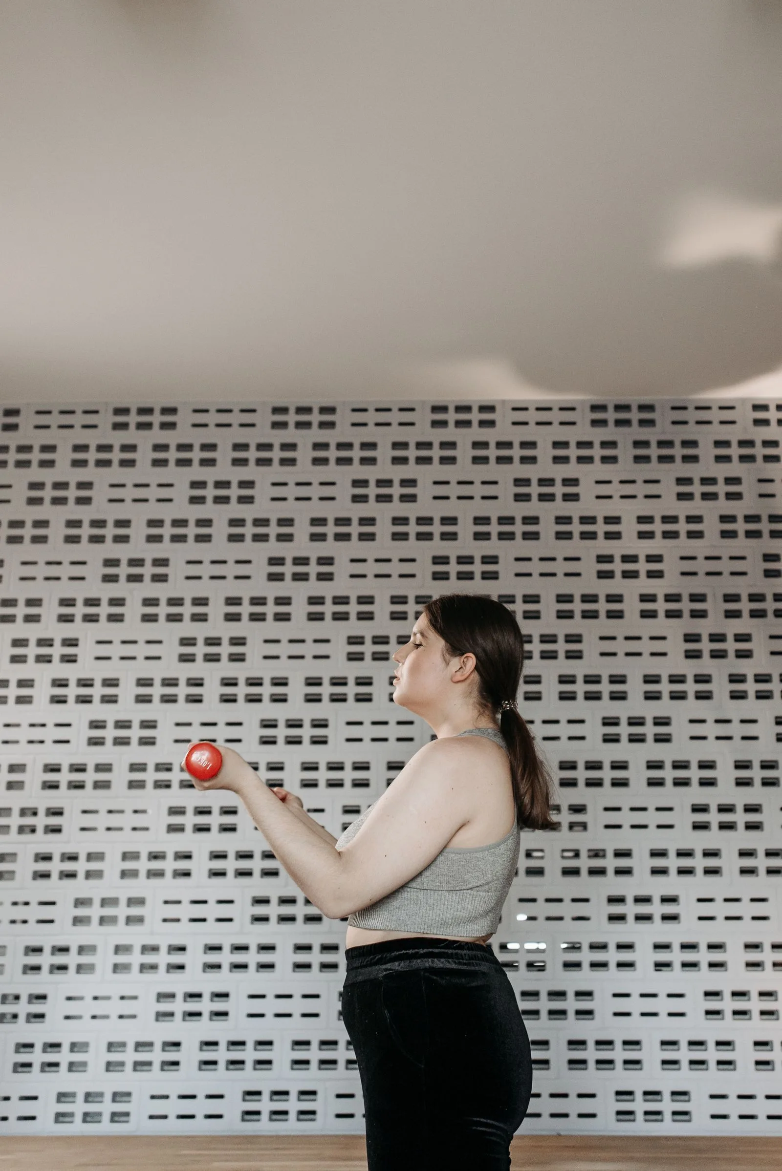 Woman lifting a dumbbell in a modern gym for strength-training context.