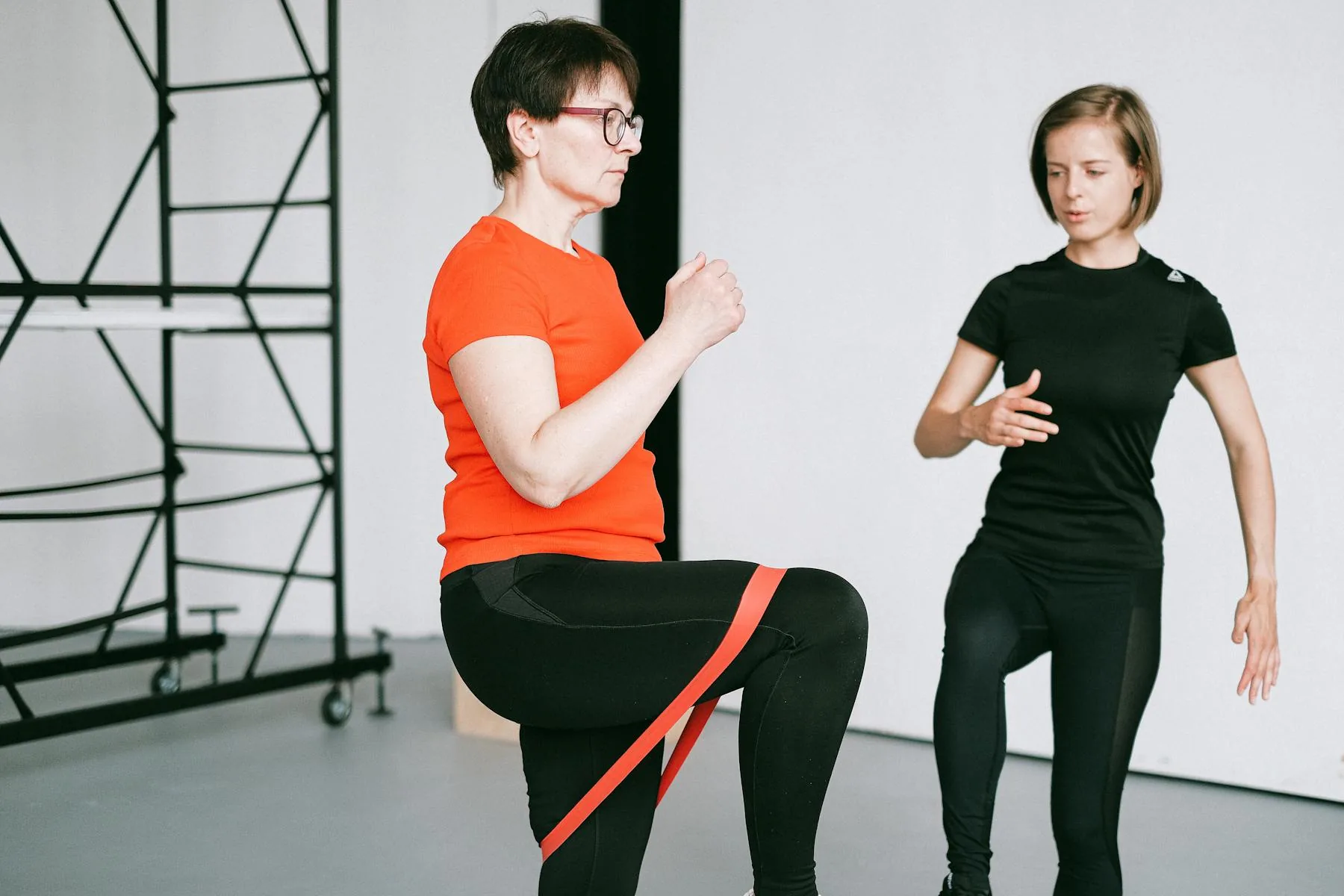 Trainer guiding a resistance band exercise in a gym.