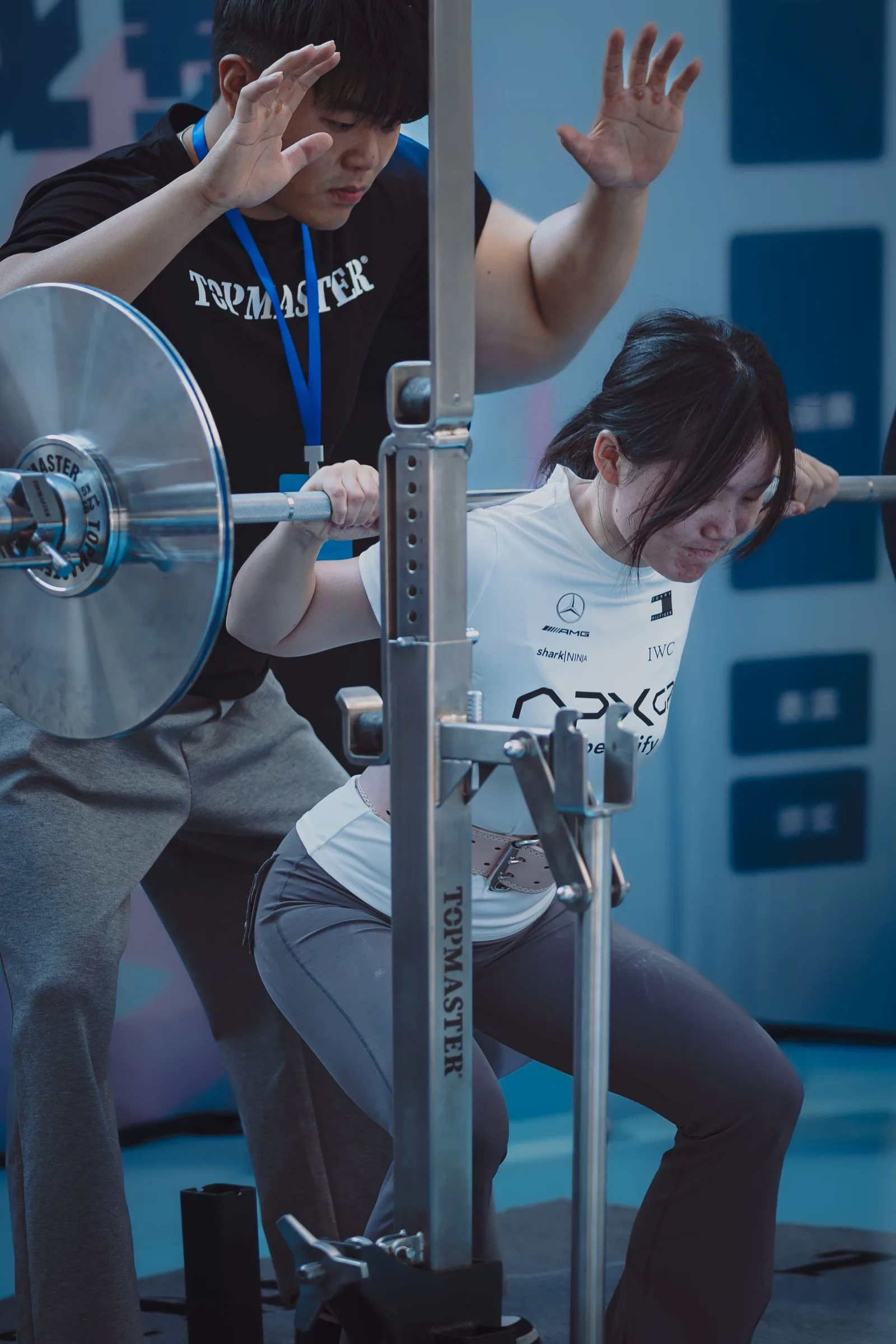 Trainer assisting a woman during a weightlifting exercise.