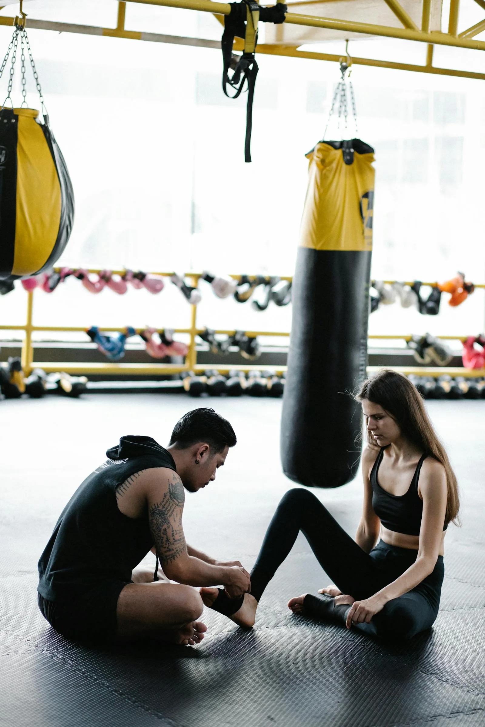 Coach helping a beginner wrap hands before a boxing session.