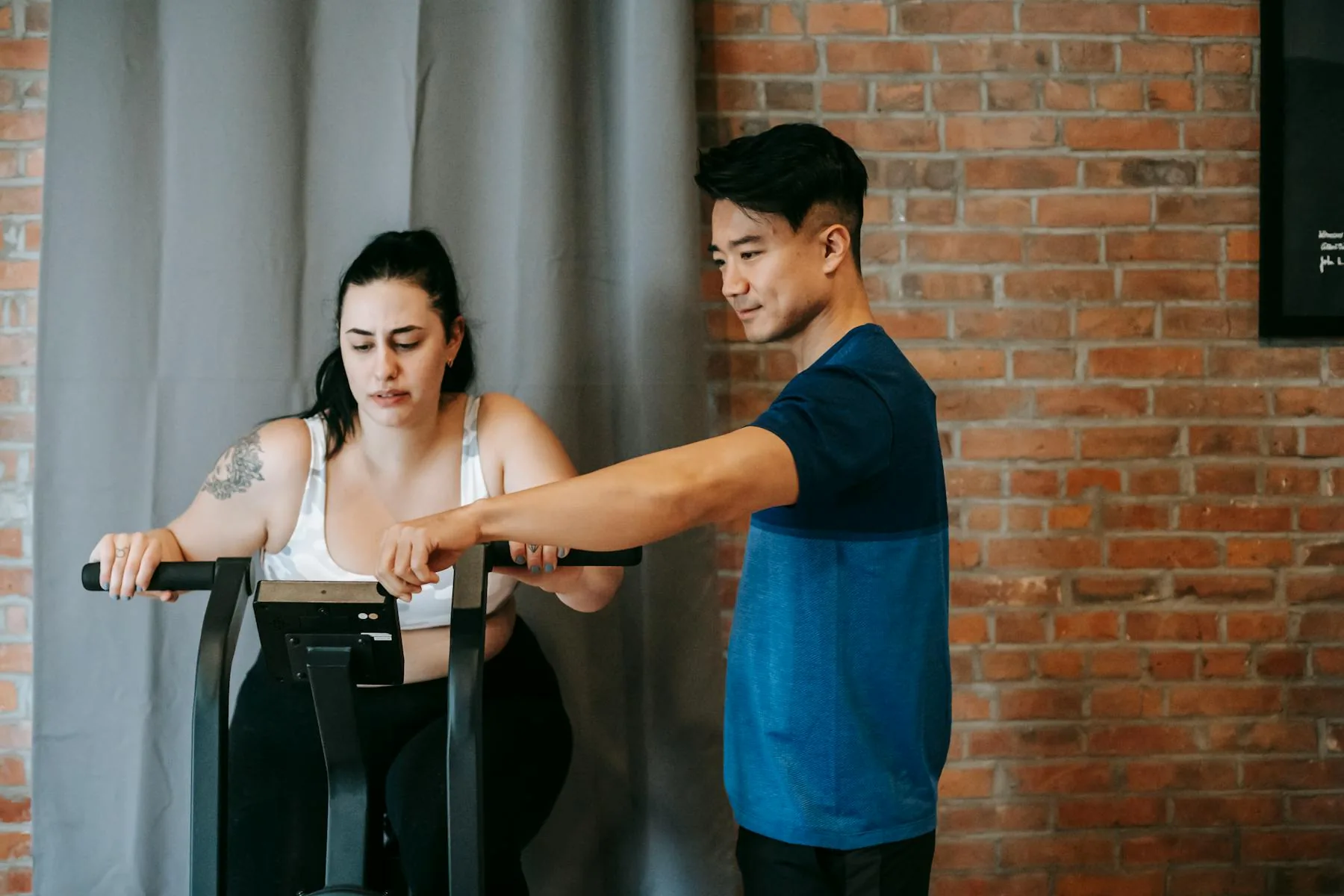 Personal trainer supporting a client during an exercise bike session.