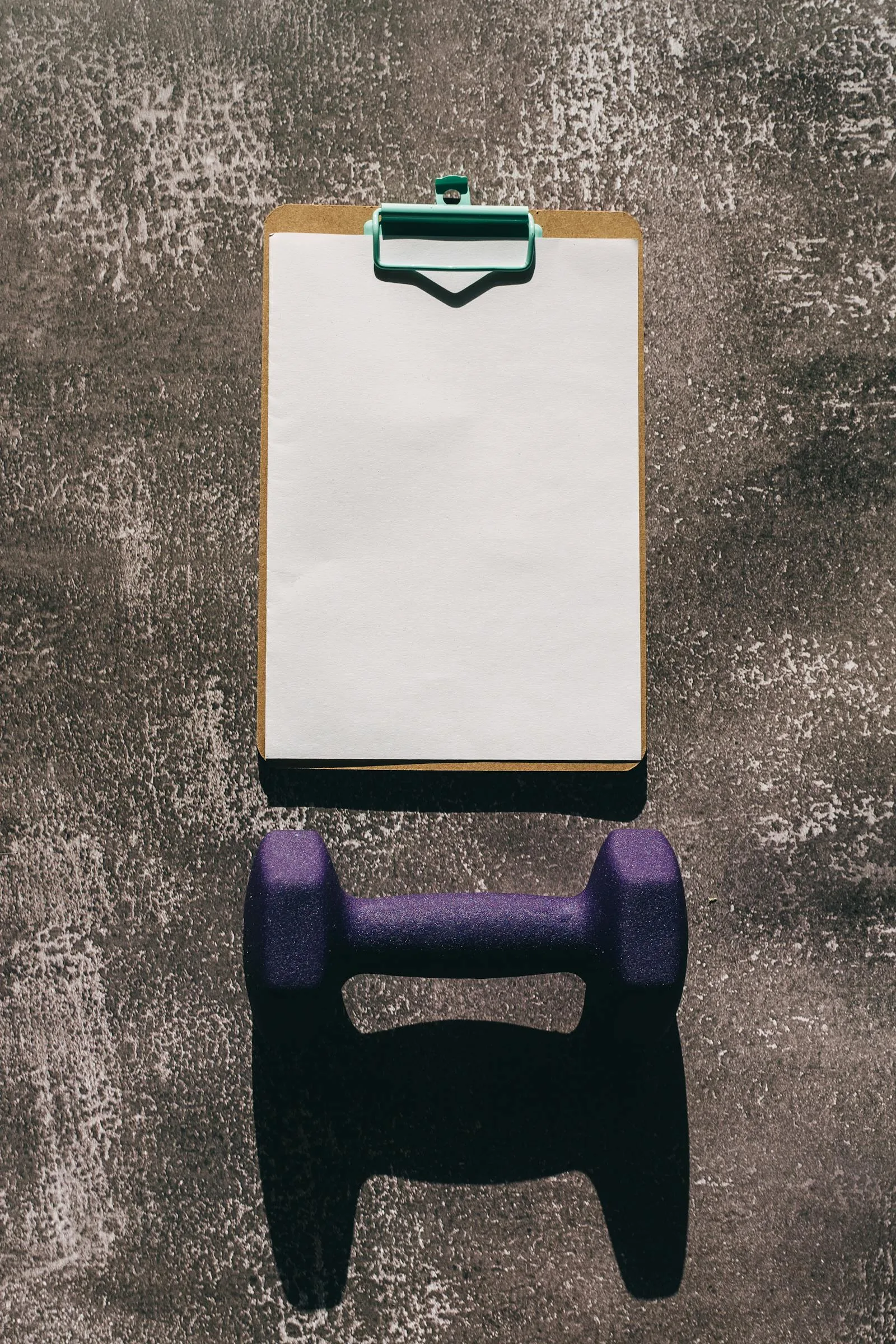 Dumbbell and workout plan clipboard used to represent choosing a structured gym.