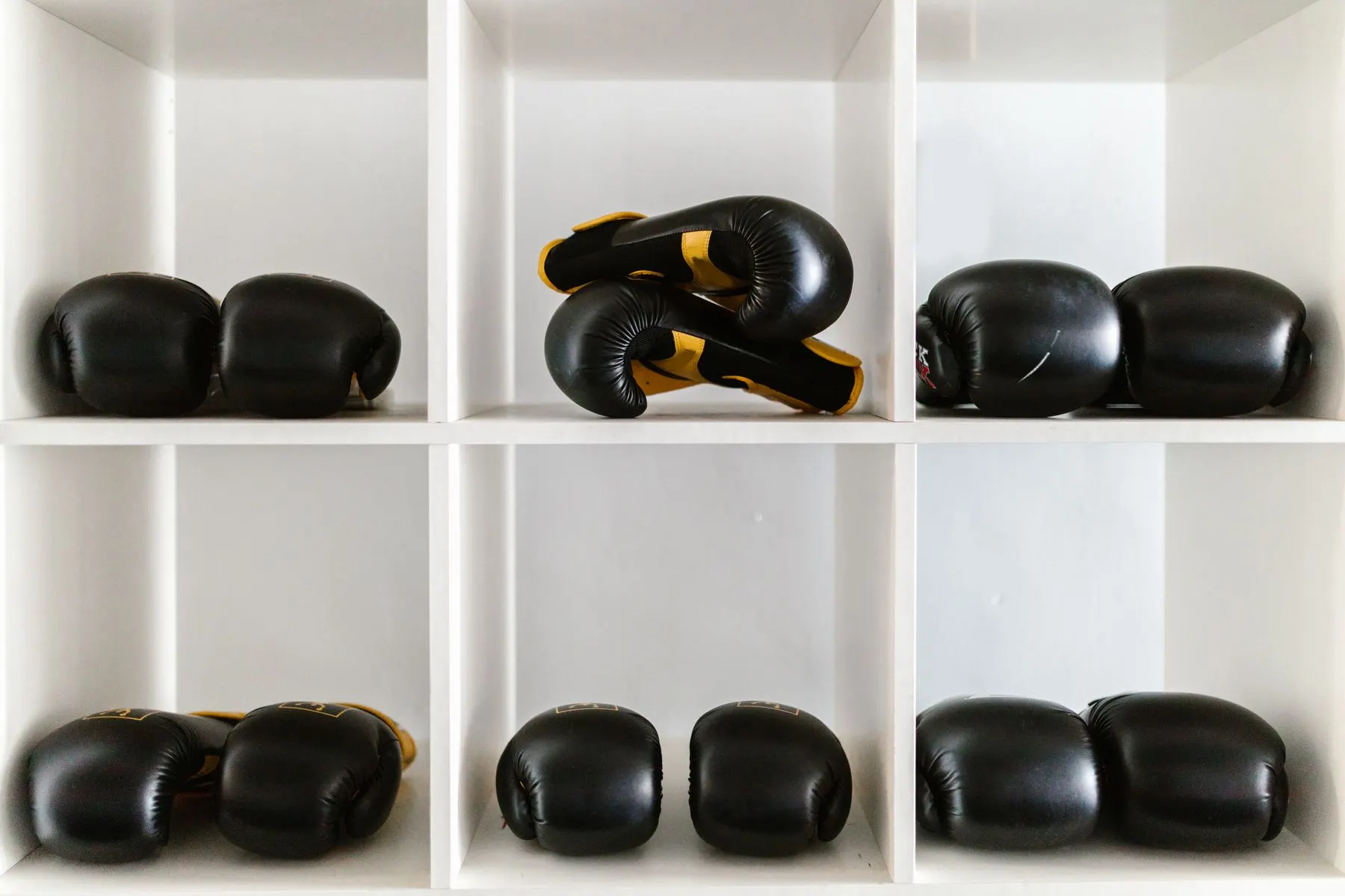 Boxing gloves stored neatly on open shelves between training sessions.
