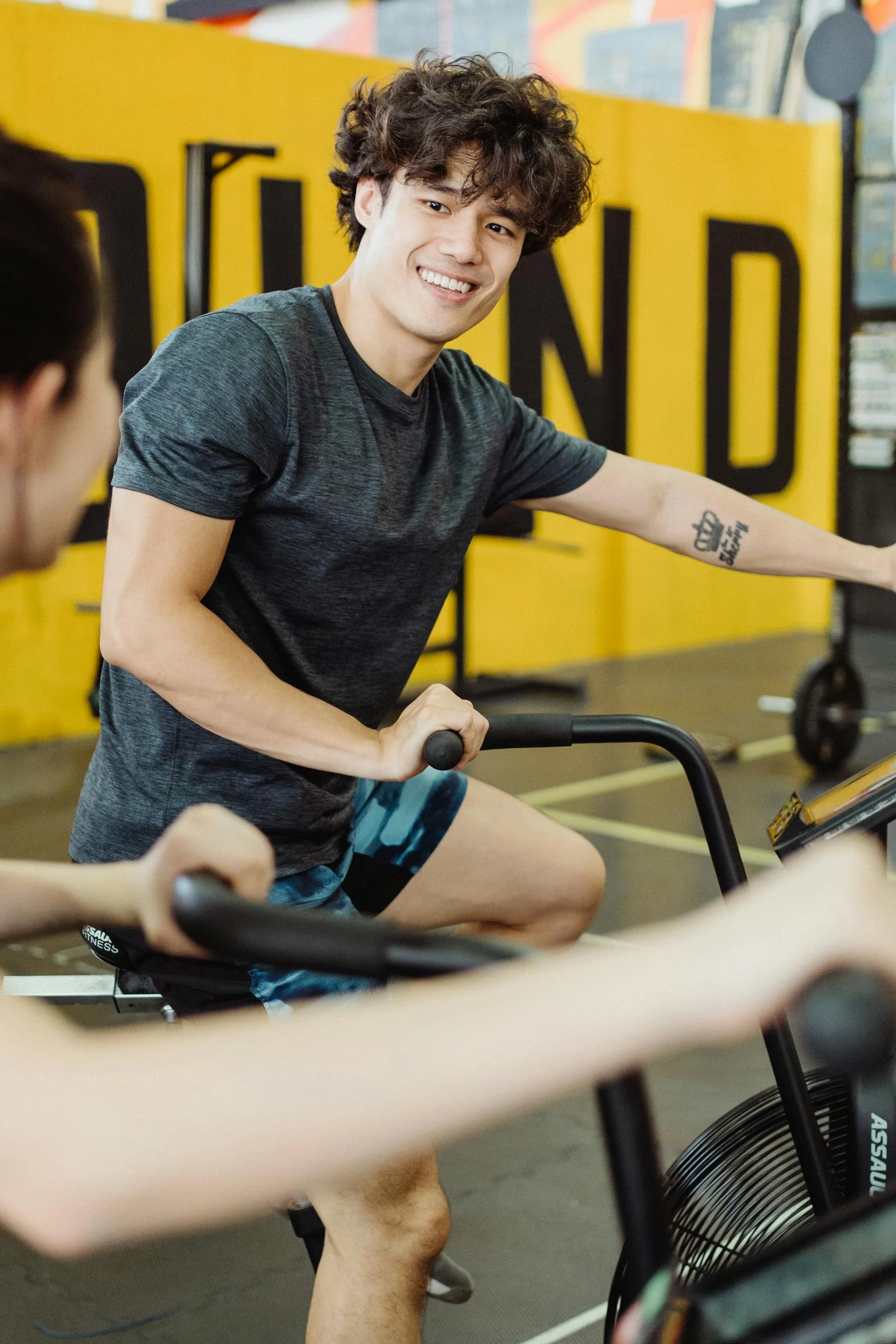 Person smiling while using an elliptical trainer indoors.