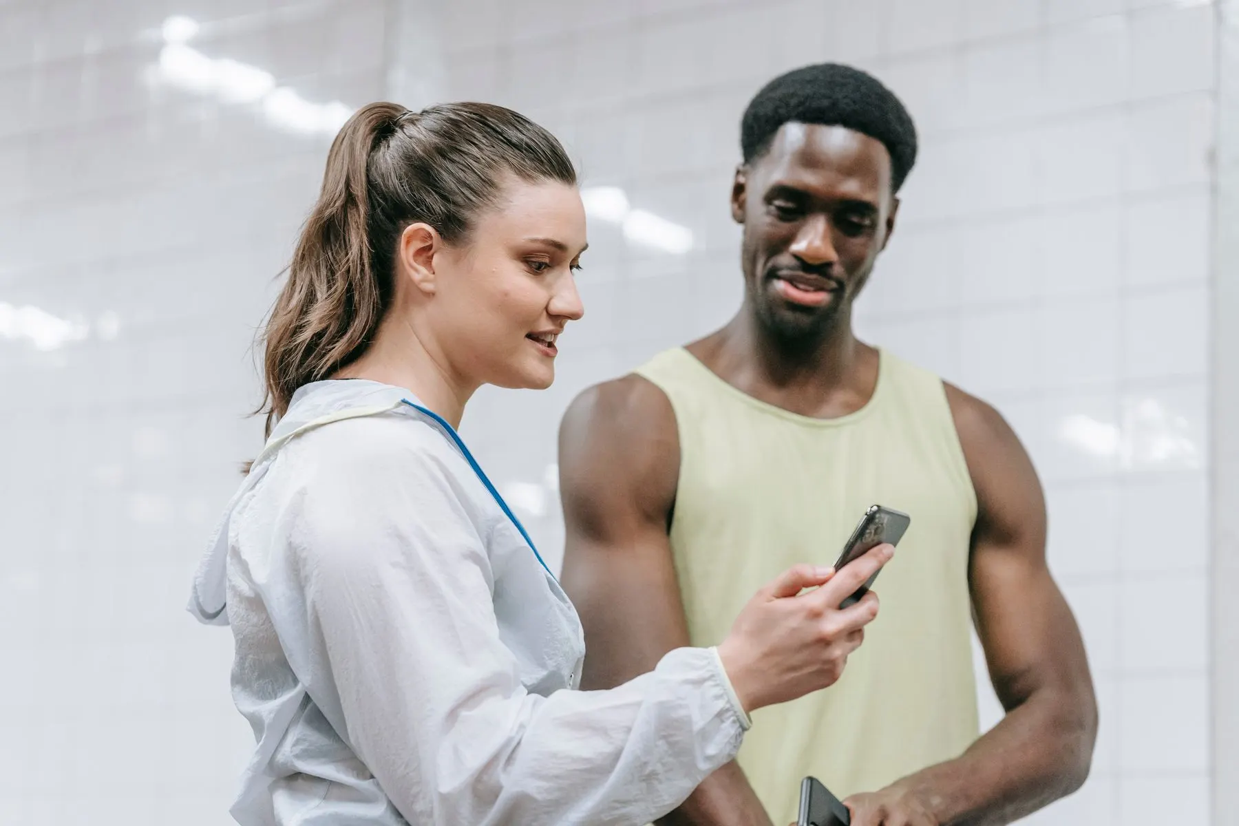 Two gym members using a phone to communicate, illustrating a quick translation question.