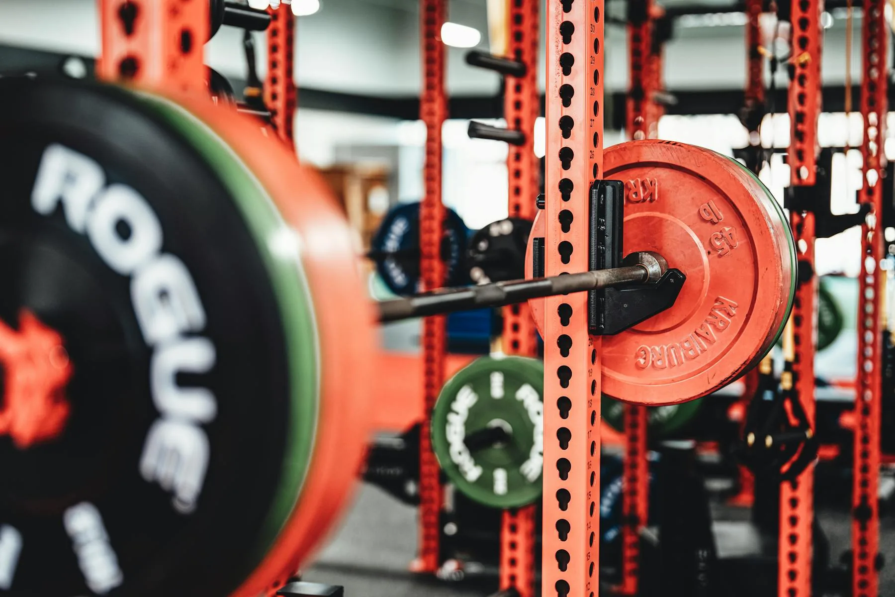 Barbell and colorful weight plates set up in a gym.