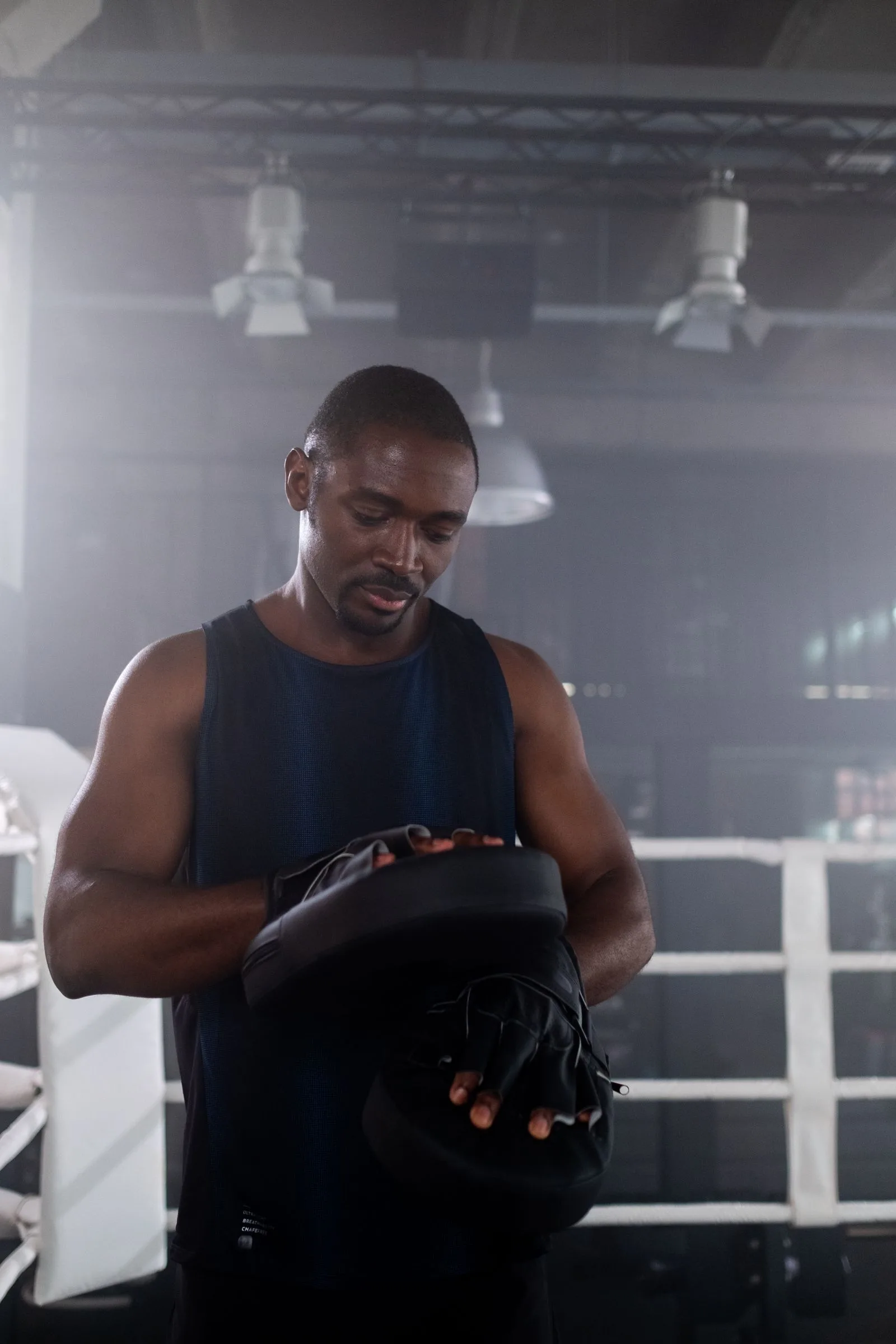 Coach holding focus mitts in a boxing gym.