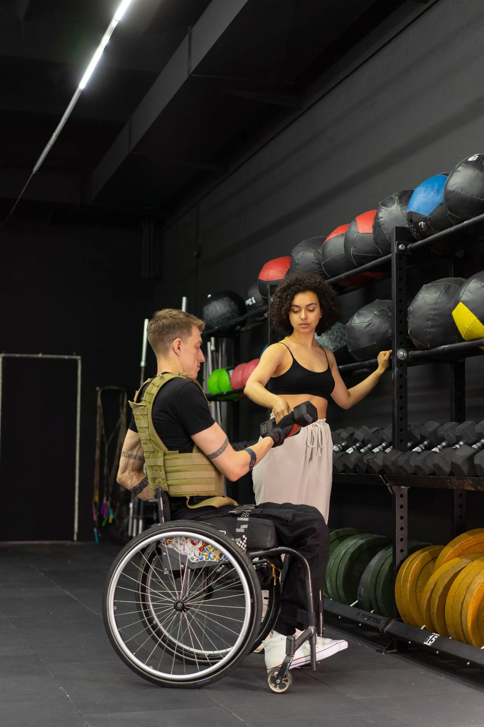 Personal trainer handing a dumbbell to a client during a coached gym session.