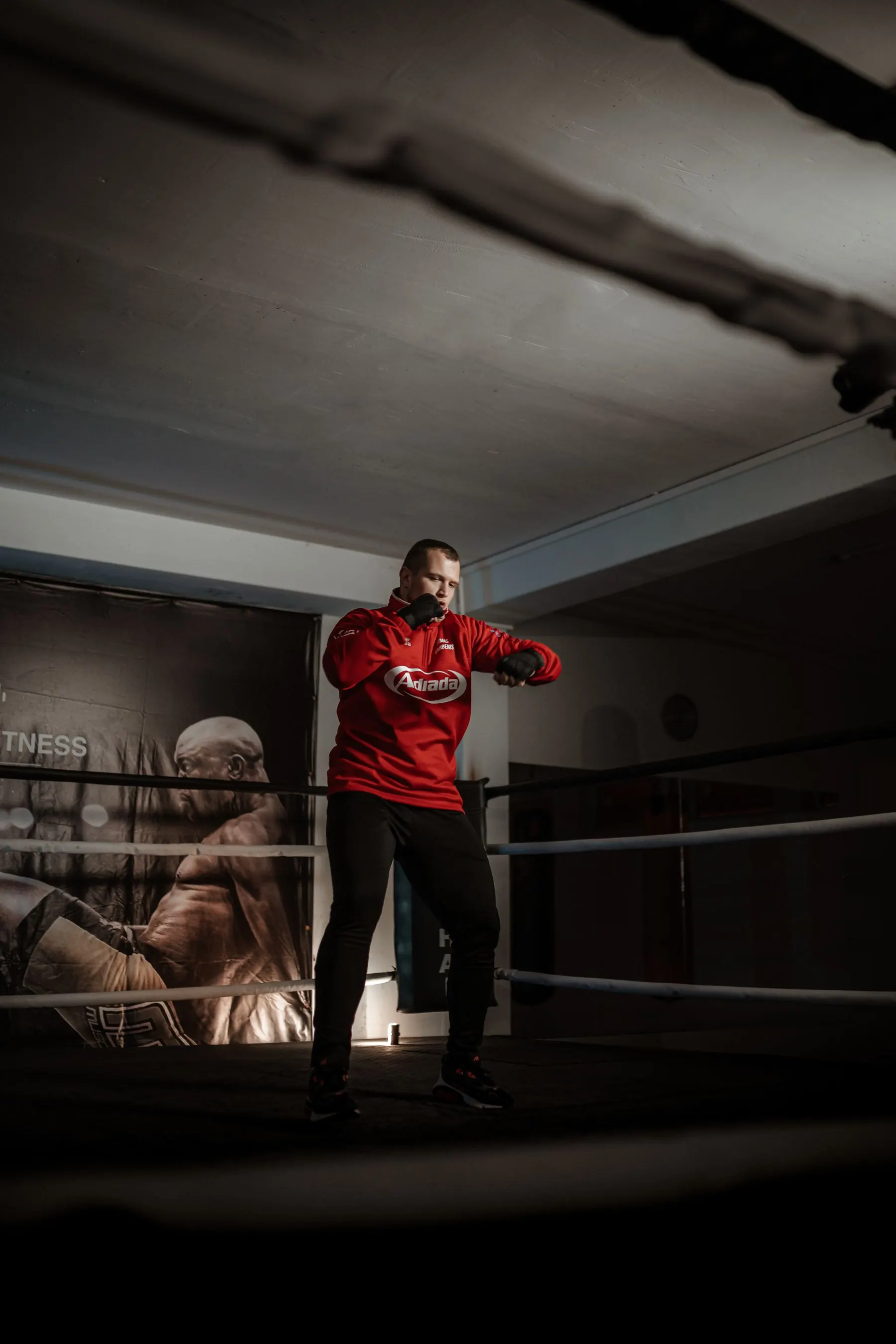 Full-body boxer practising movement from a balanced stance in a ring.