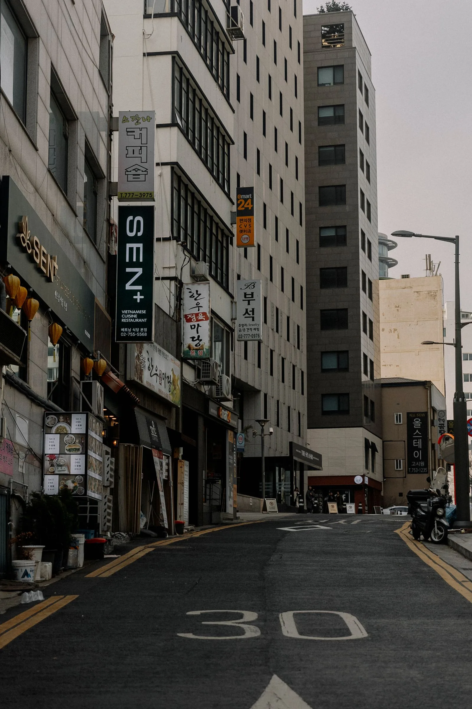 Urban Seoul street view with storefronts and city buildings.