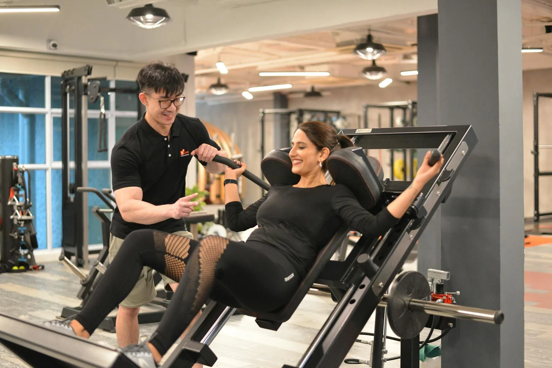 Trainer instructing a woman on a leg press machine.