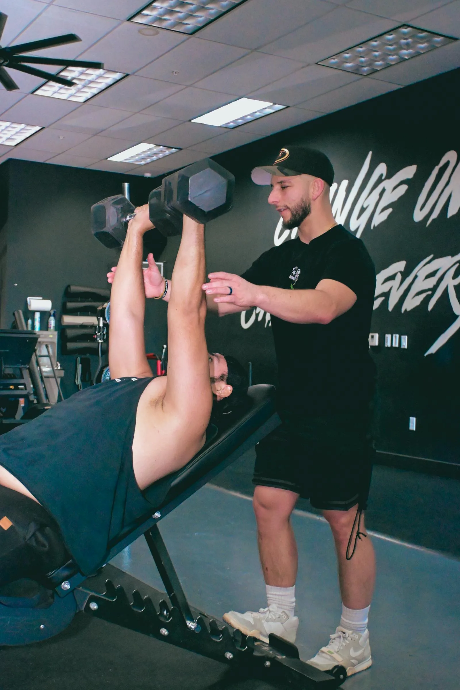 Trainer assisting a dumbbell exercise for safe strength training.