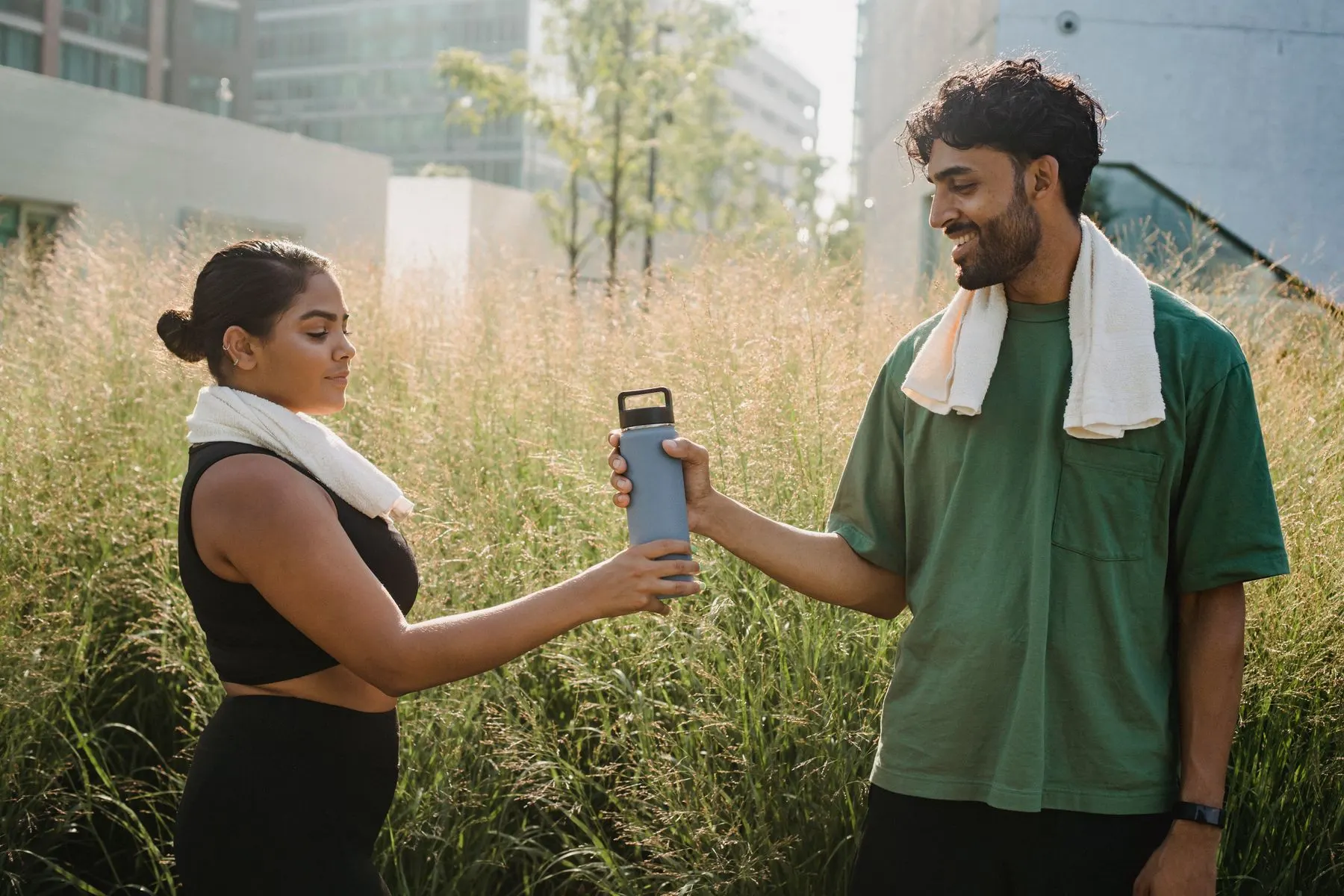 Two people taking a hydration break during warm-weather outdoor exercise.