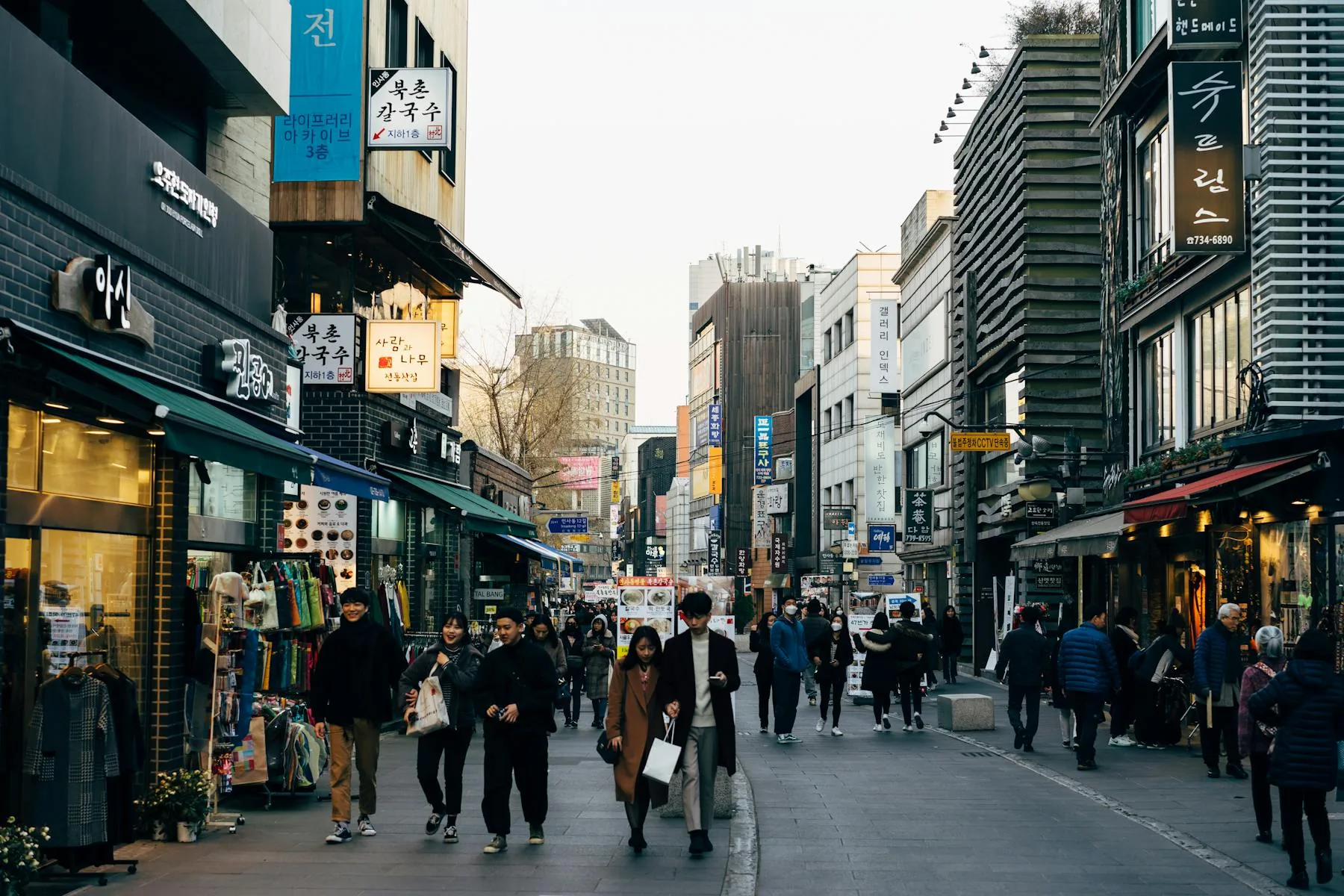 Busy Seoul shopping street with people walking during the day.